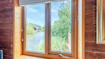 Eine Holzhütte mit einem Fenster, das auf einen Fluss und grüne Vegetation blickt.