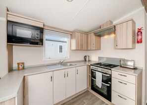 A compact kitchen with a microwave, stove, oven, and toaster.