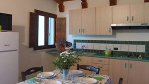 A kitchen with wooden cabinets, a tiled backsplash, and a dining table set for four. - LE CASTELLA RESIDENCE APP. 7 (Santa Domenica)