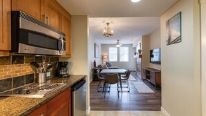 A modern kitchen with a built-in microwave, stove, and dishwasher, leading to a dining area with a table and chairs. - Fraser Crossing/Founders Pointe, Condo 1 Bedroom w/Kitchenette Premium Unit 4547 (Winter Park)