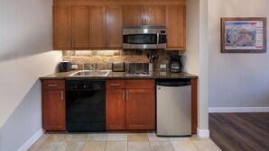 A modern kitchen with wooden cabinets, a stainless steel microwave, a dishwasher, and a tiled backsplash. - Fraser Crossing/Founders Pointe, Condo 1 Bedroom w/Kitchenette Premium Unit 4547 (Winter Park)