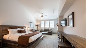 Une chambre à coucher avec un grand lit, un canapé, un bureau et un ventilateur de plafond.