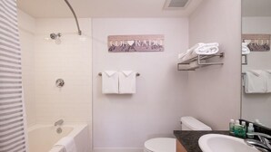 Une salle de bain avec une baignoire, des toilettes et un lavabo. Des serviettes sont accrochées au mur, et il y a une pancarte sur laquelle on peut lire « Colorado ».