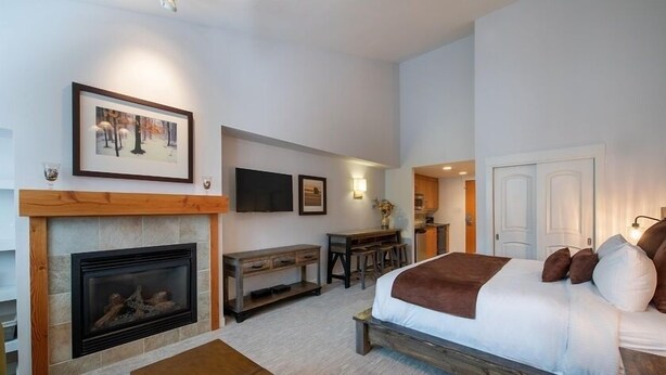 Une chambre avec un grand lit, une cheminée, un bureau et un téléviseur.