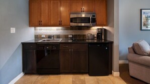 Une cuisine compacte avec des meubles en bois, un four à micro-ondes en acier inoxydable et une machine à café.