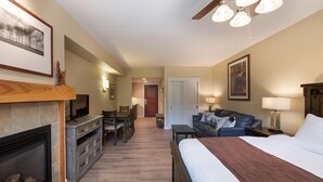 Quarto de hotel com lareira, cama, sofá, escrivaninha e área de jantar.