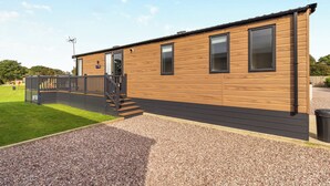 Ein Holz-Mobilheim mit Terrasse, Treppe und einem Kiesweg.