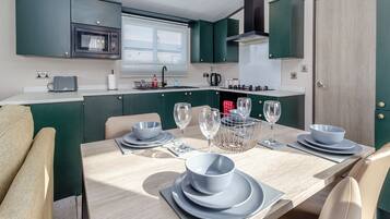 A compact kitchen with a dining table set for four, a microwave, and a window with blinds.