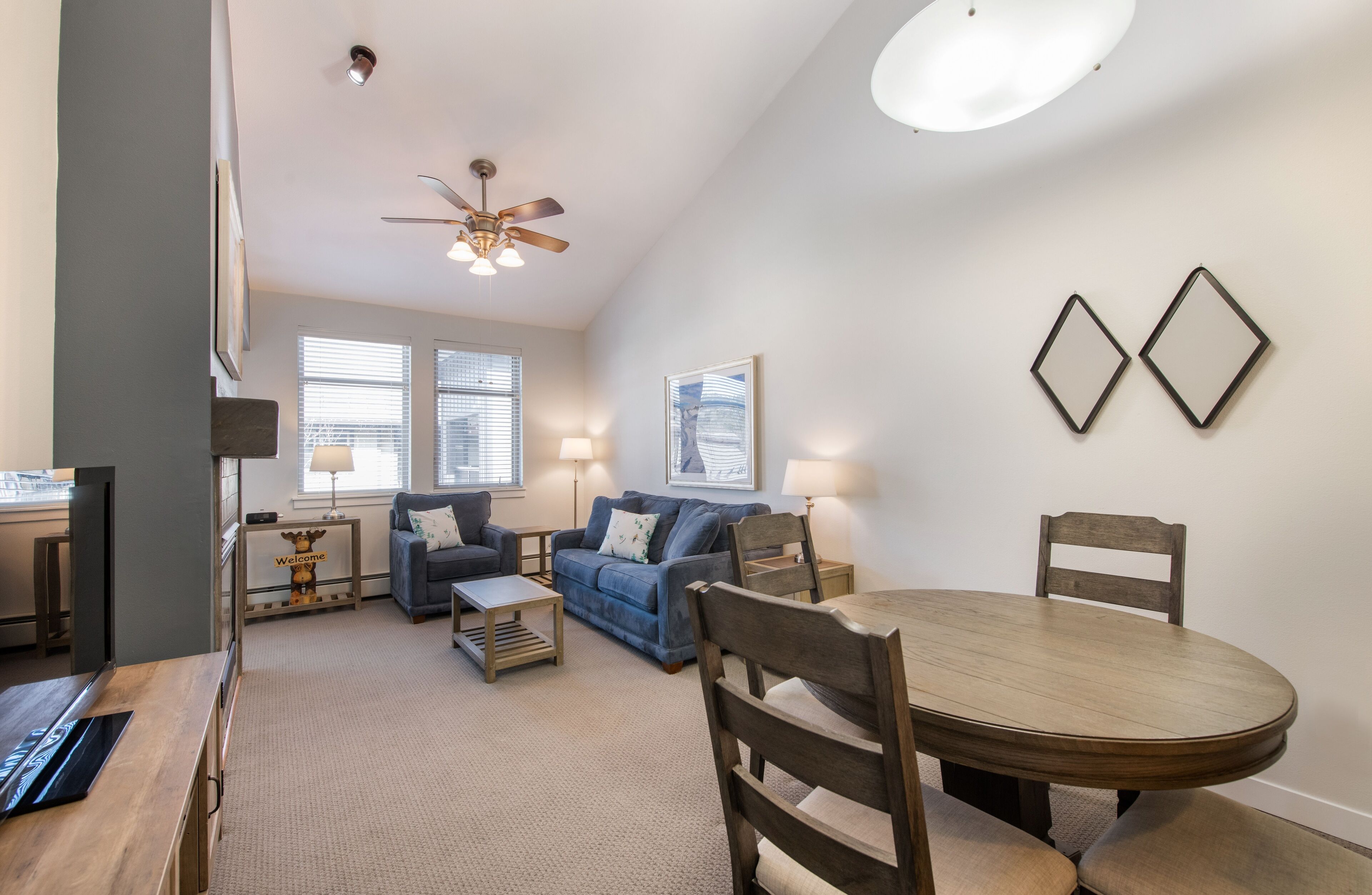 A living room with a wooden dining table, two sofas, a coffee table, and a ceiling fan.