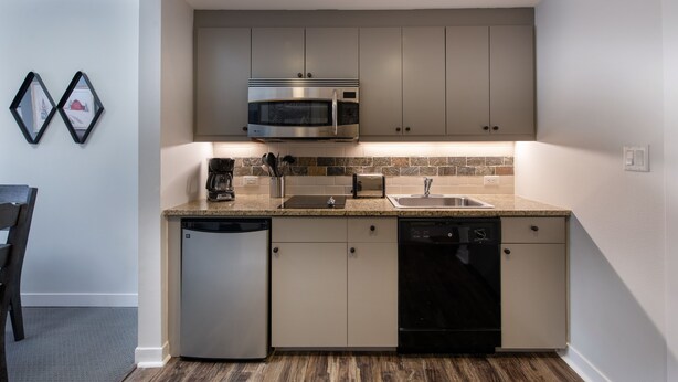 Una cocina compacta con microondas integrado, lavavajillas y un lavabo.