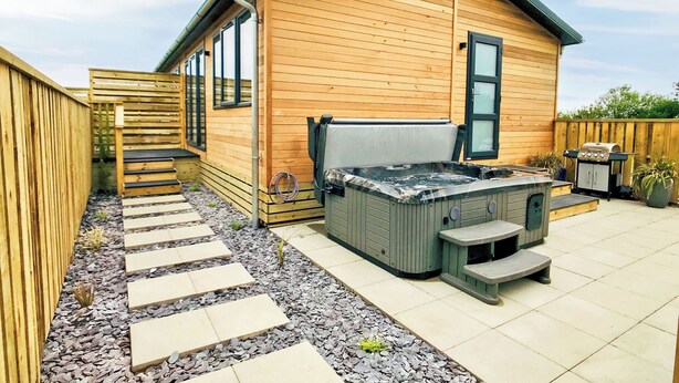 Eine Holzhütte mit Whirlpool, Grill und Terrasse mit trittsteinfreundlichem Zugang.