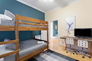 Una camera con un letto a castello, una scrivania con un computer e una televisione.