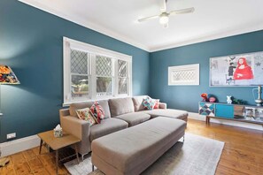 A living room with a sectional sofa, a small table, a cabinet, and a ceiling fan.