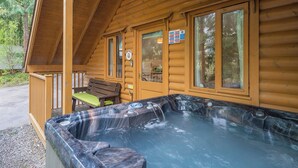 A wooden cabin with a hot tub, a bench, and a window with a sign. - 3 bedroom accommodation in Webbery, Bideford (Webbery, Bideford)