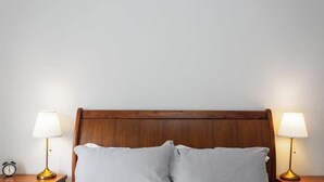 Un lit avec une tête de lit en bois, deux lampes de chevet et une table de chevet avec une horloge.