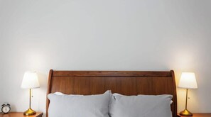 A bed with a wooden headboard, two bedside lamps, and a nightstand with a clock. - Modern Family Home w/ Large Backyard & Fast WiFi (Cowes)