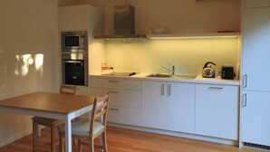 Uma cozinha compacta com micro-ondas, fogão, pia e chaleira no balcão.