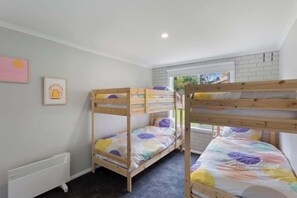 Een kamer met stapelbedden, een radiator, een raam en een lijst met een afbeelding aan de muur.