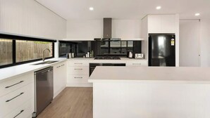 Una cocina moderna con armarios blancos, electrodomésticos de acero inoxidable y una isla central.