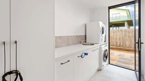 Un área de lavandería con lavadora, secadora y lavabo.