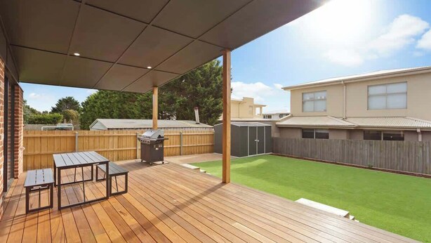 Una terraza techada al aire libre con una parrilla y una mesa de picnic.