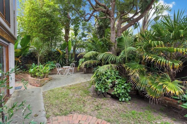 Un jardín con un patio, una mesa y sillas.