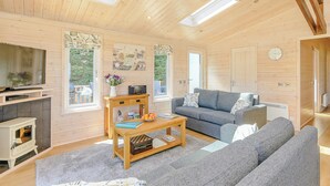 A cozy cabin interior with a sofa, a coffee table, a TV, and a fireplace. - Luxurious lodge with stunning countryside views. (Ashover)