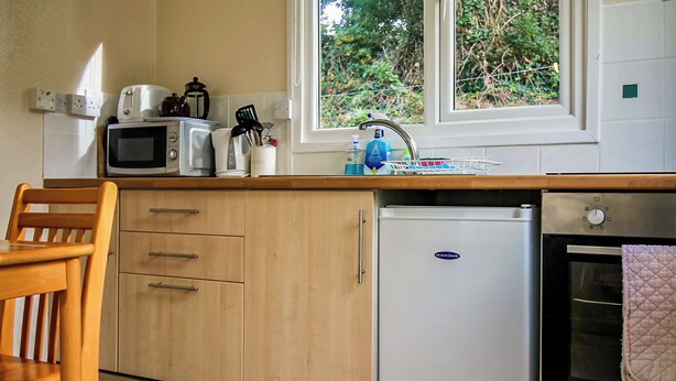 A compact kitchen with a microwave, toaster, sink, and a small refrigerator.