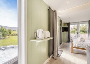 A bedroom with a bed, a TV, a hot tub, and a view of a garden.