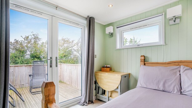 A bedroom with a bed, a desk, and a window with curtains.