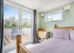 A bedroom with a bed, a desk, and a window with curtains.