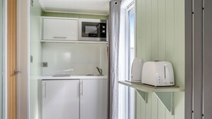 A compact kitchen with a microwave, toaster, and cabinets.