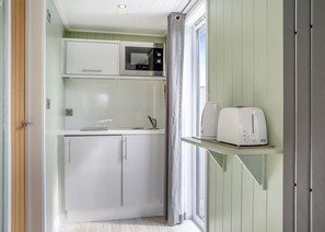 A compact kitchen with a microwave, toaster, and cabinets.