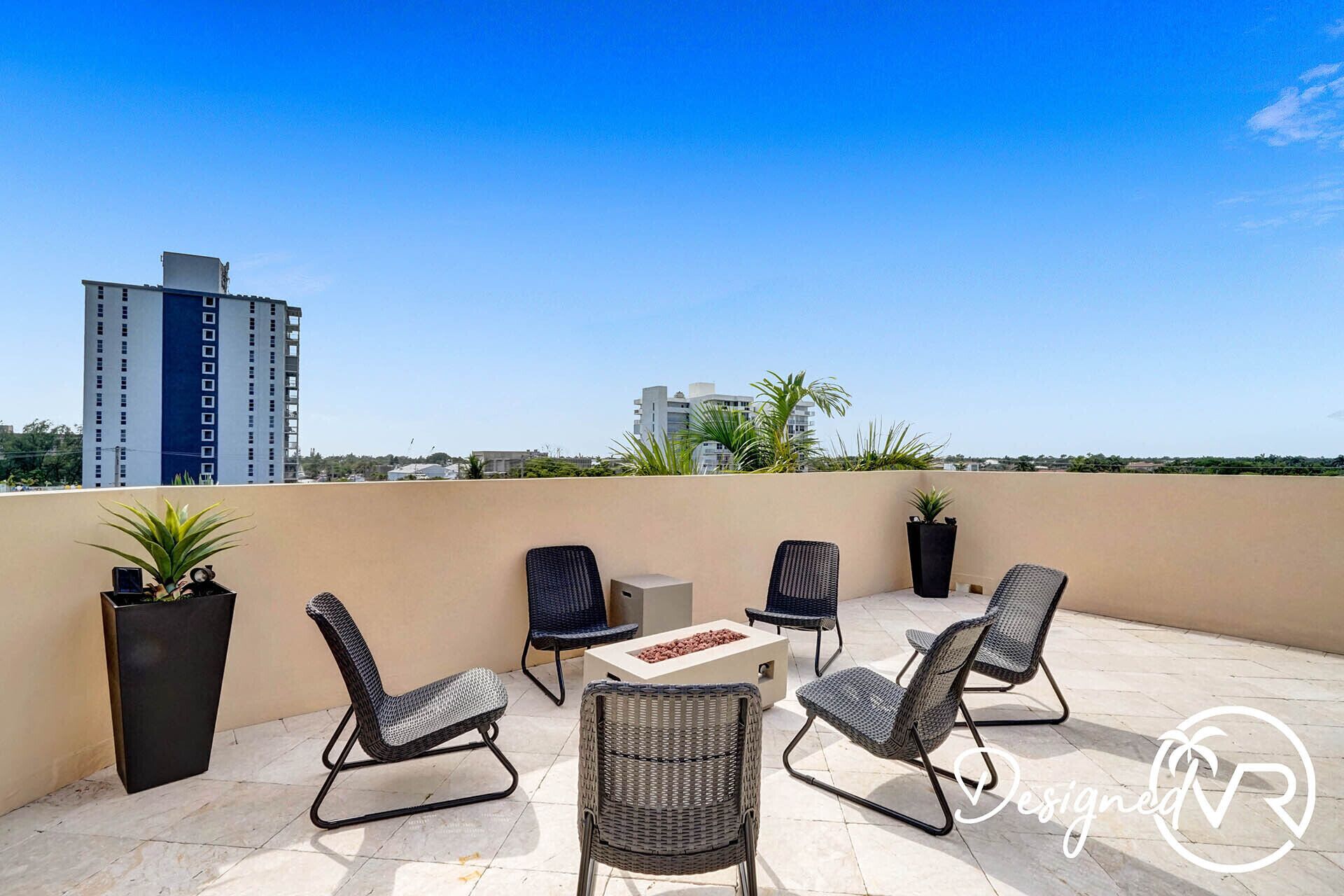 Una terraza en la azotea con mobiliario exterior, incluyendo sillas y una mesa, y plantas en macetas.