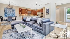 A modern living room with a grey sectional sofa, a white coffee table, and a dining area with a black table and chairs. - The Nia Tower Ultimate Beach House (Pompano Beach)