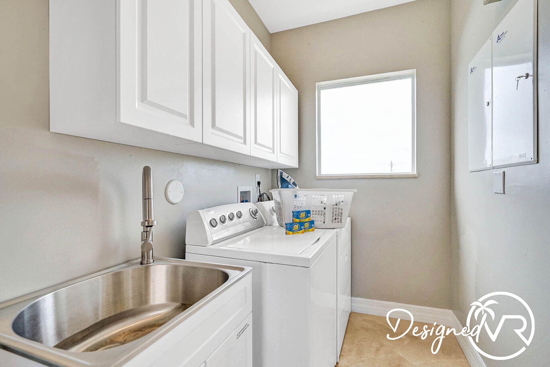 A modern kitchen with white cabinetry, a stainless steel sink, and a built-in washing machine.