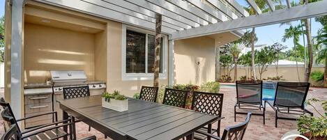 An outdoor patio with a grill, table, and chairs.