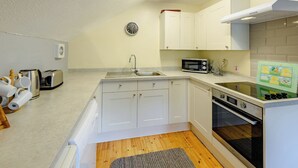 A compact kitchen with white cabinets, a microwave, a toaster, and a sink. - Timber lodge set by the lake with one double and one twin. (Webbery, Bideford)