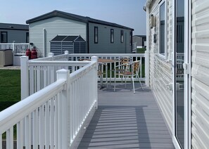 Una terraza techada al aire libre con baranda blanca, una mesa y dos sillas.