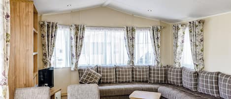 A cozy living area with a sofa set, a wooden table, and a television.