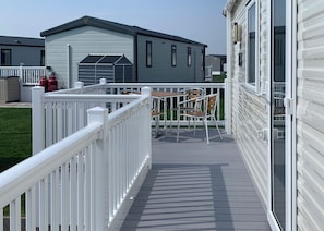 Una terraza techada al aire libre con baranda blanca, una mesa y dos sillas.
