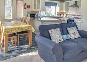 A modern kitchen with a dining area, a sofa, and a table with a yellow tablecloth.
