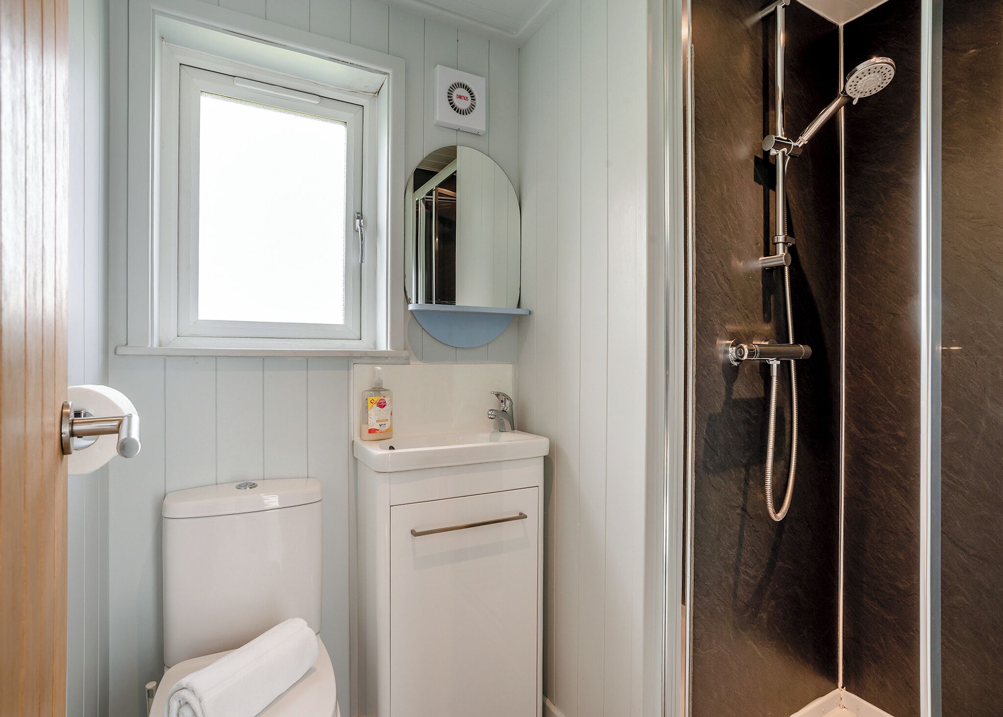 Une salle de bain équipée de toilettes, d’un lavabo, d’un miroir et d’une douche.