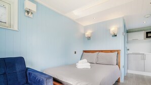 Une chambre avec un lit, une chaise, une télévision et un coin cuisine.