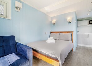 A bedroom with a bed, a chair, a TV, and a kitchenette. - 1 bedroom accommodation in Great Busby (Great Busby)