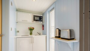 Une cuisine de taille réduite avec des meubles blancs, un four à micro-ondes, un grille-pain et un vase rempli de fleurs posé sur le plan de travail.