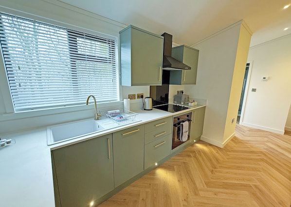 Eine moderne Küche mit Fenster, Spüle und integriertem Backofen.