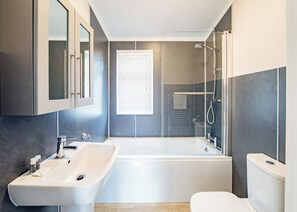 A modern bathroom with a bathtub, a sink, and a toilet. - 2 bedroom accommodation in Hunstanton (Hunstanton)