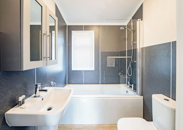 A modern bathroom with a bathtub, a sink, and a toilet. - 2 bedroom accommodation in Hunstanton (Hunstanton)
