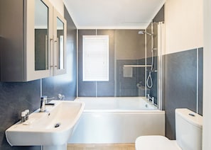 A modern bathroom with a bathtub, a sink, and a toilet.
